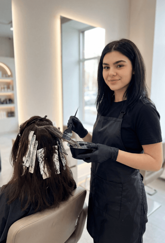 Парикмахер делает мелирование в фольге, наносит краску кистью в салоне