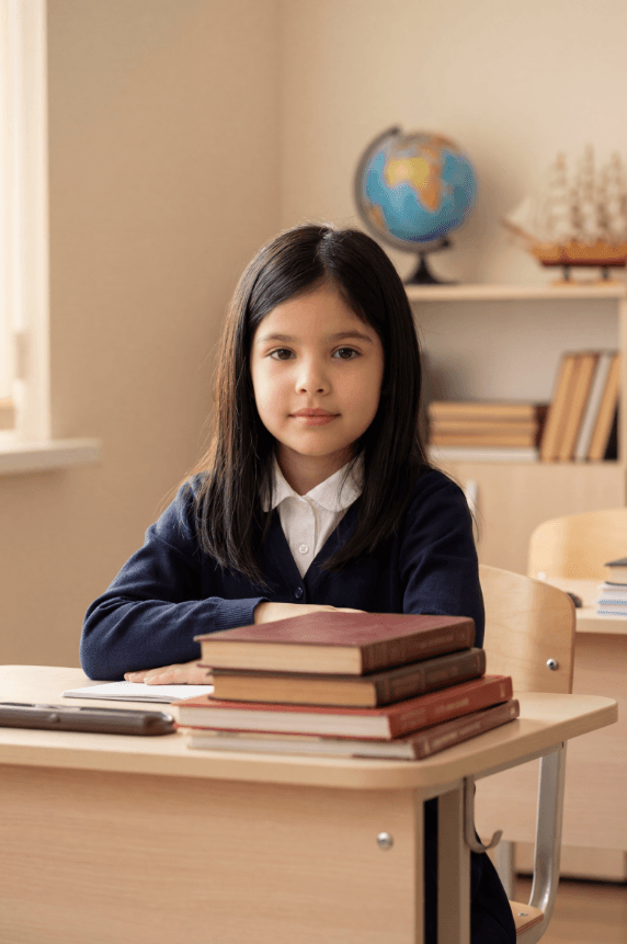 Ребенок сидит за партой со стопкой книг, глобус на полке