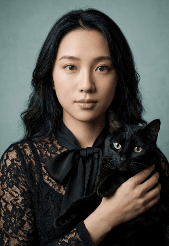Студийный портрет женщины в черном кружеве, держащей черную кошку с зелеными глазами