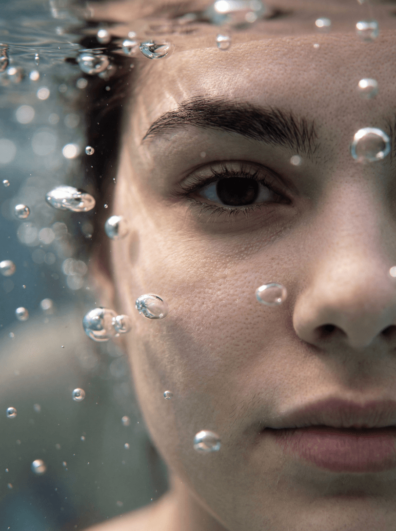 Крупный план лица человека под водой с пузырьками воздуха.