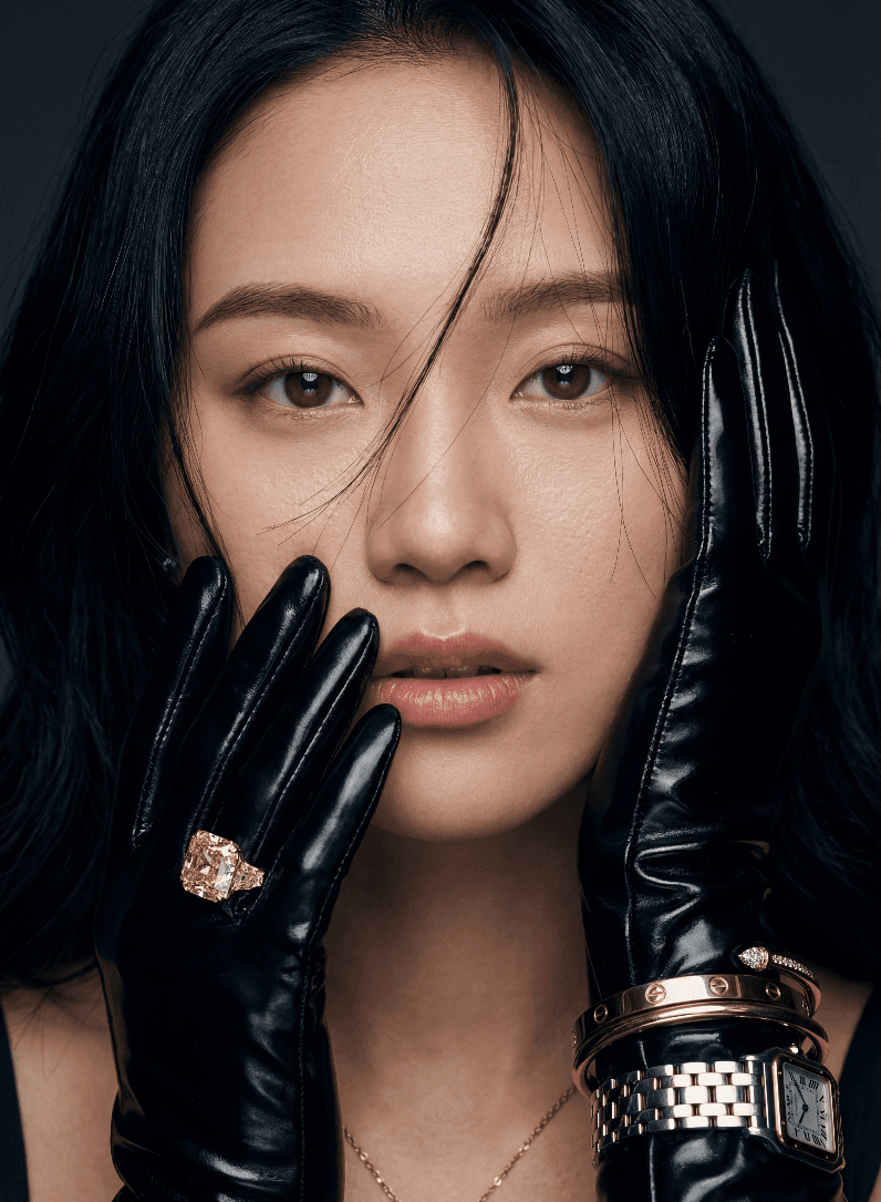 Крупный план женщины в черных кожаных перчатках с желтым бриллиантом и золотыми часами.