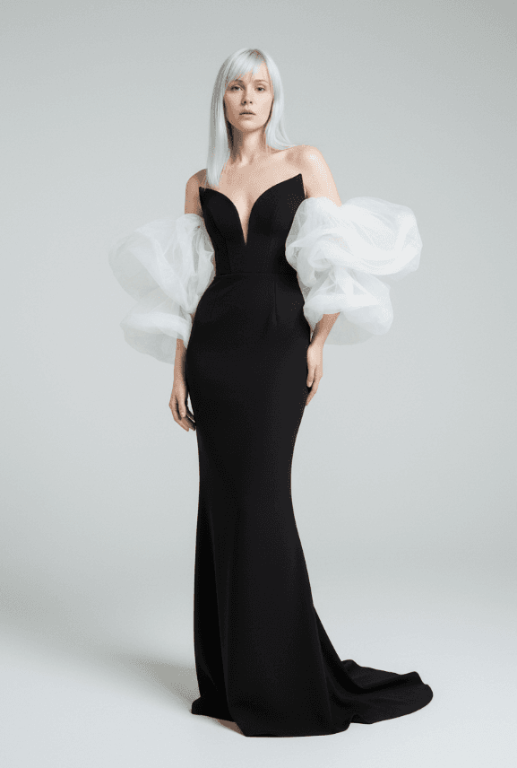 Модель в черном платье-бюстье в пол с глубоким V-образным вырезом и белыми тюлевыми рукавами