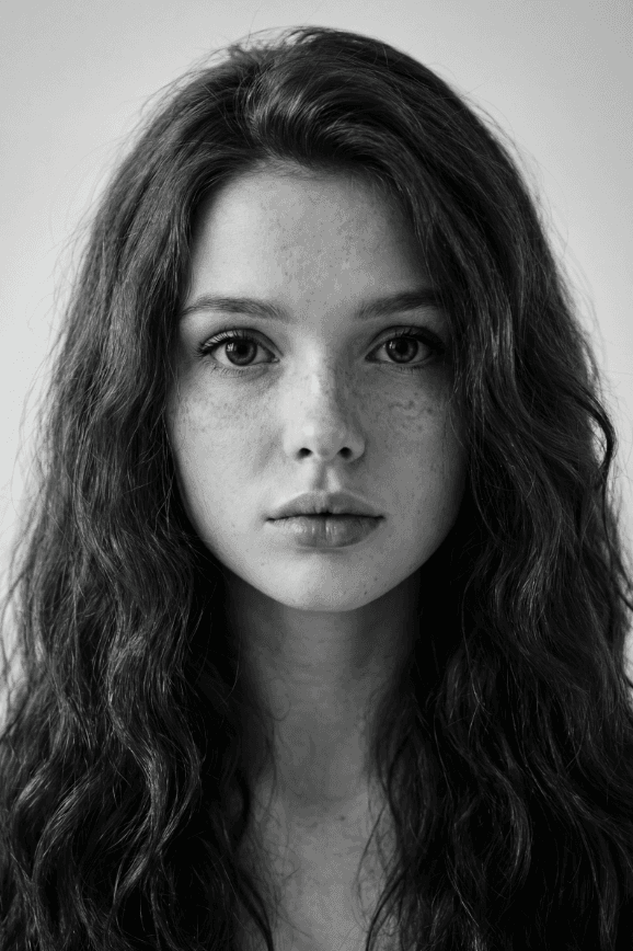 Черно-белый портрет женщины с веснушками и длинными волнистыми волосами