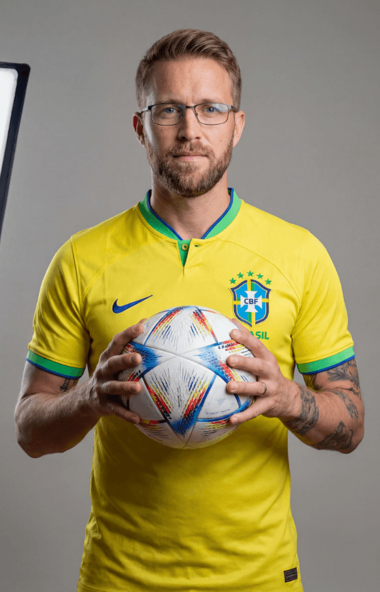Мужчина в форме сборной Бразилии держит футбольный мяч