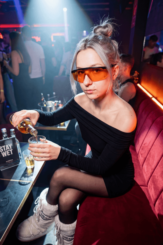 Человек в оранжевых очках наливает напиток в стакан в клубе