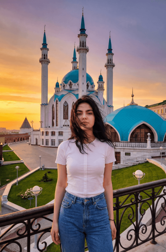 Молодая женщина перед голубыми куполами мечети на закате