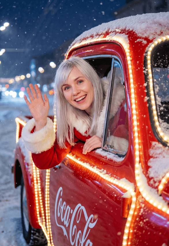 Улыбчивая женщина машет из красного грузовика Coca-Cola на заснеженной улице ночью